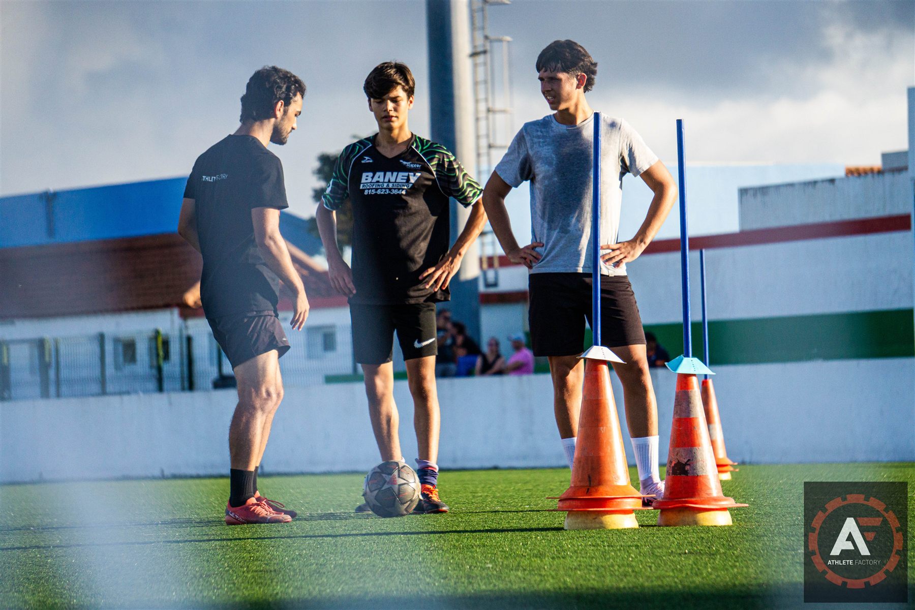 Treinador Athlete Factory a orientar dois jogadores no campo